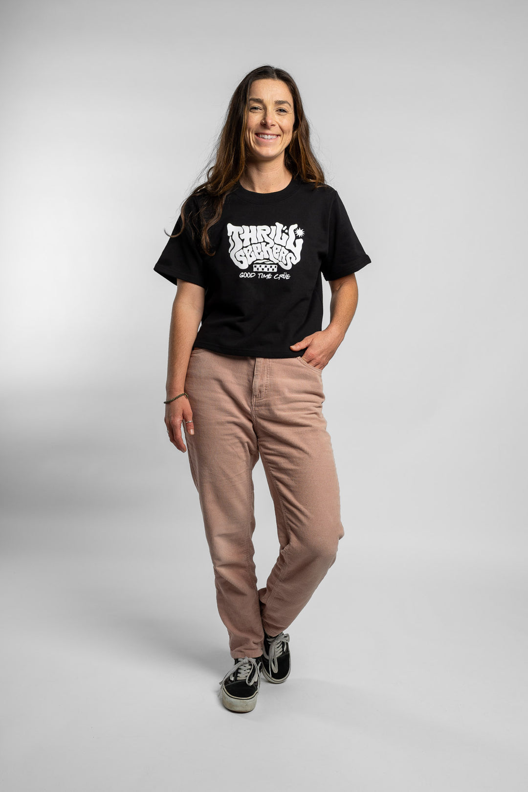 Woman wearing a black crop with 'Thrill Seekers' logo on a white background