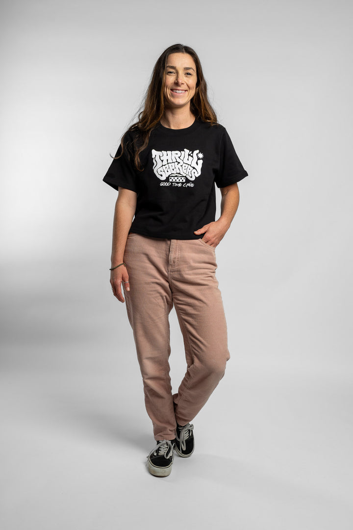 Woman wearing a black crop with 'Thrill Seekers' logo on a white background