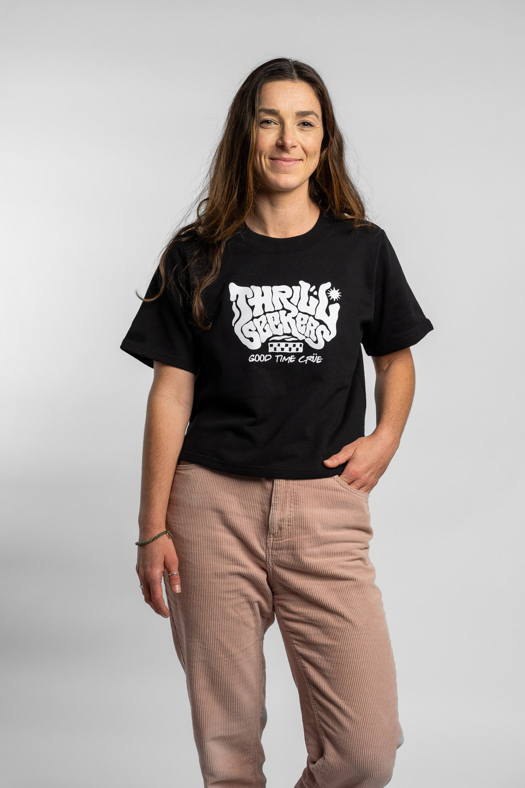 Woman wearing a black crop with 'Thrill Seekers' logo on a white background