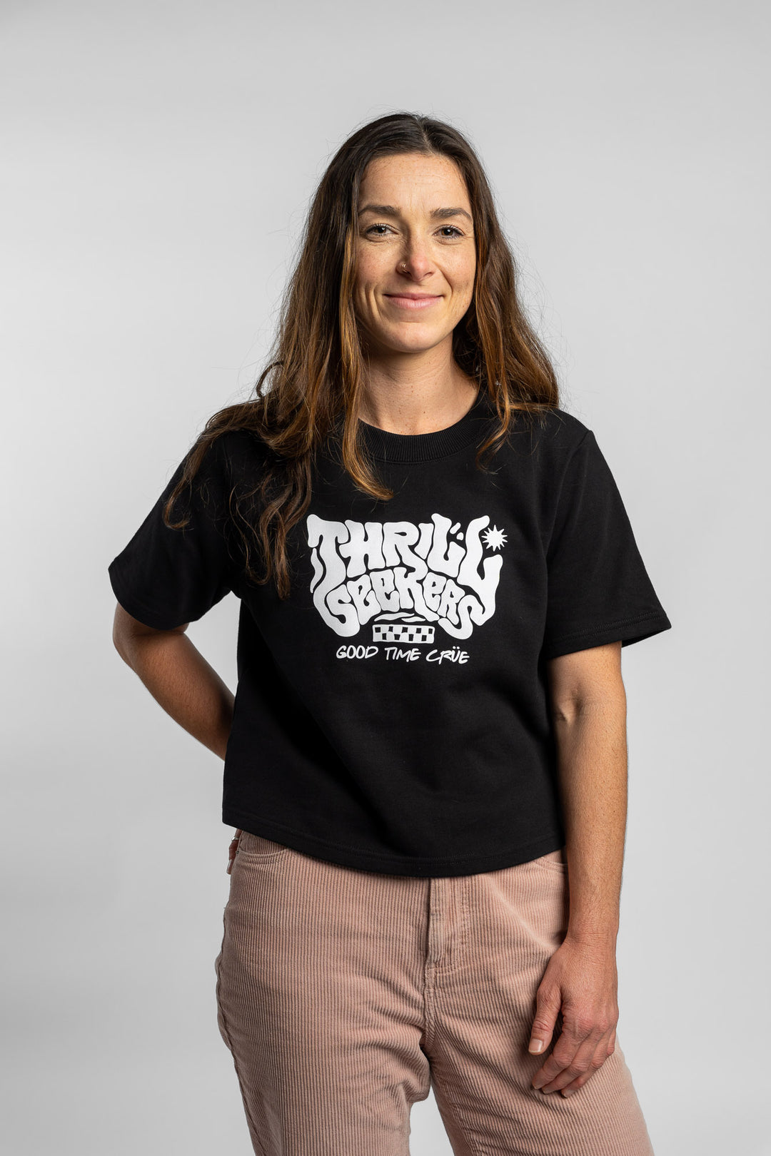 Woman wearing a black crop with 'Thrill Seekers' logo on a white background