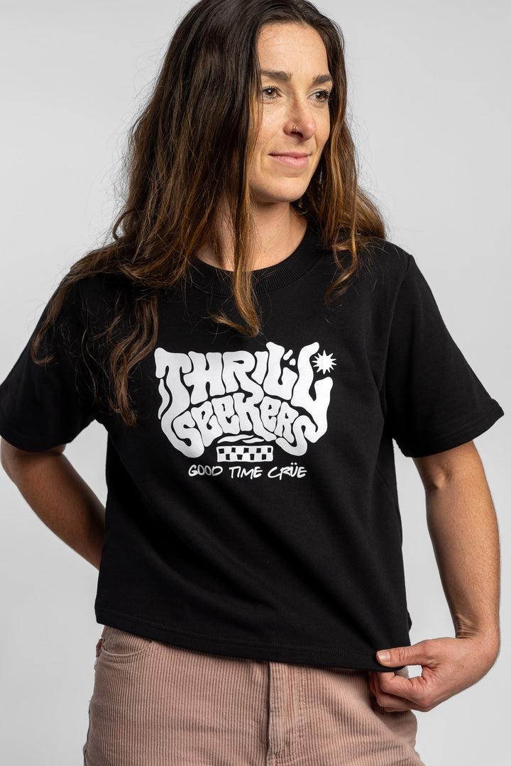 Woman wearing a black crop with 'Thrill Seekers' logo on a white background