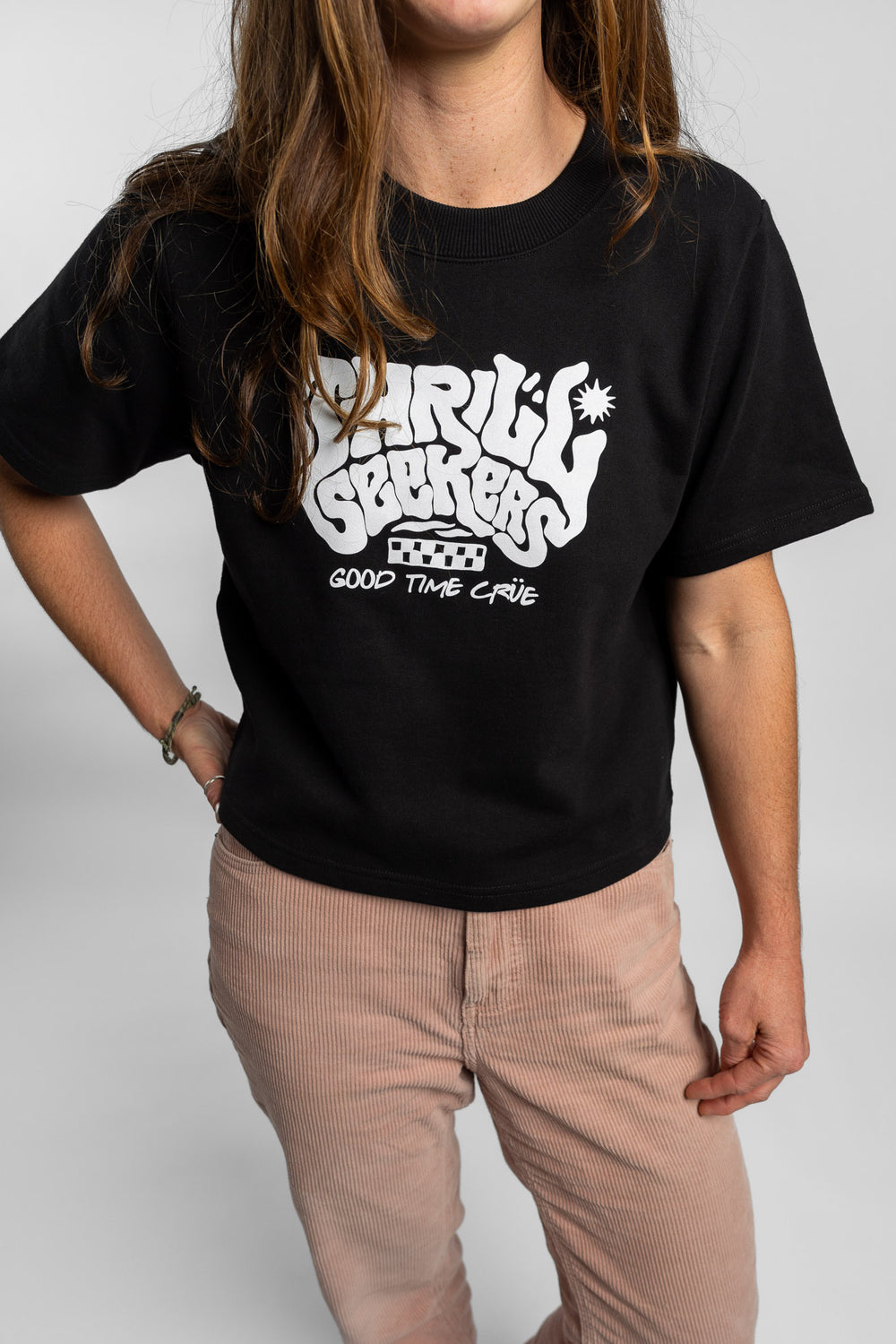 Woman wearing a black crop with 'Thrill Seekers' logo on a white background