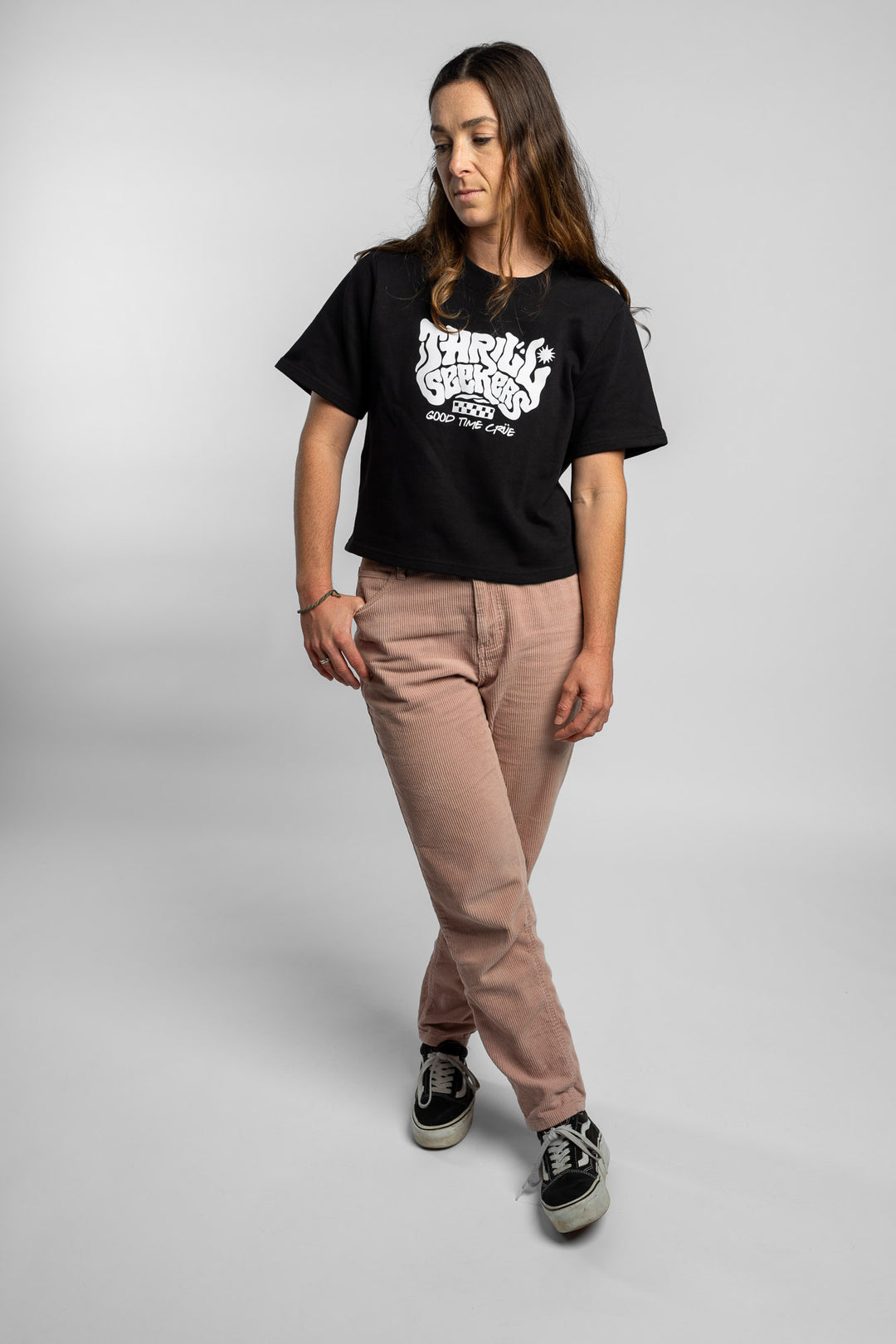 Woman wearing a black crop with 'Thrill Seekers' logo on a white background